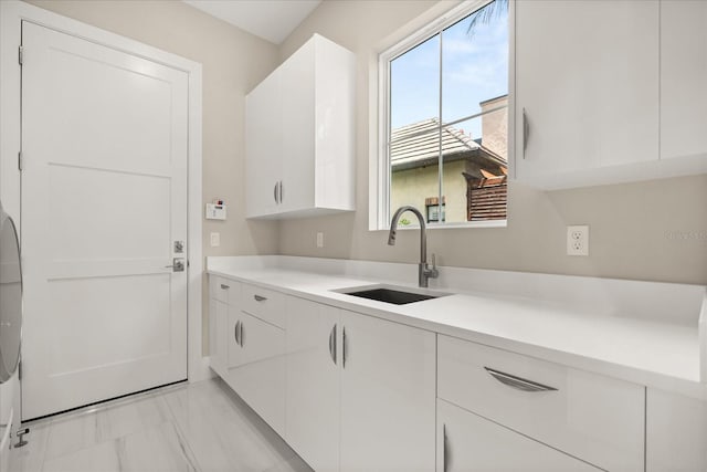 laundry room featuring a sink, cabinet space, marble finish floor, and a wealth of natural light