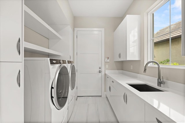 laundry room featuring washer and clothes dryer, a sink, and cabinet space