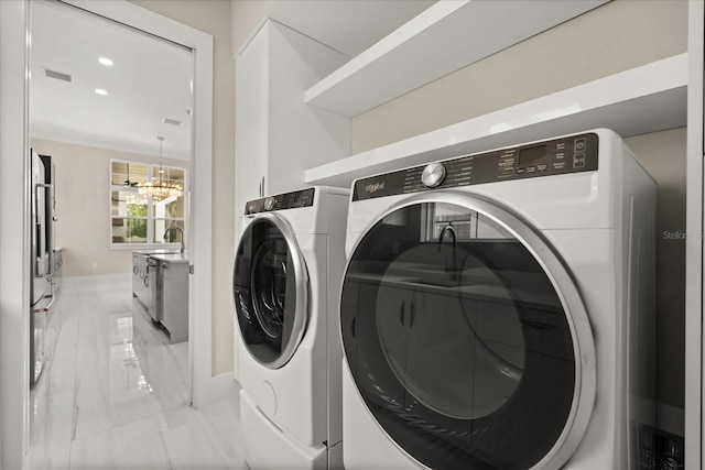 washroom with laundry area, a notable chandelier, marble finish floor, baseboards, and washing machine and dryer