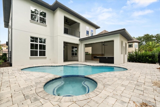 back of property with a ceiling fan, a balcony, a patio area, and stucco siding