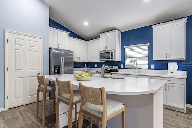 kitchen with white cabinetry, an island with sink, appliances with stainless steel finishes, and a breakfast bar