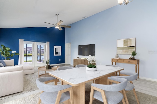 dining space with high vaulted ceiling, light hardwood / wood-style floors, ceiling fan, and french doors