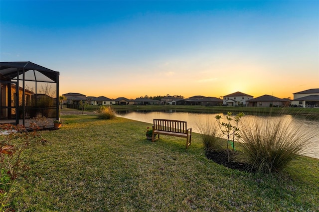 yard at dusk with glass enclosure and a water view