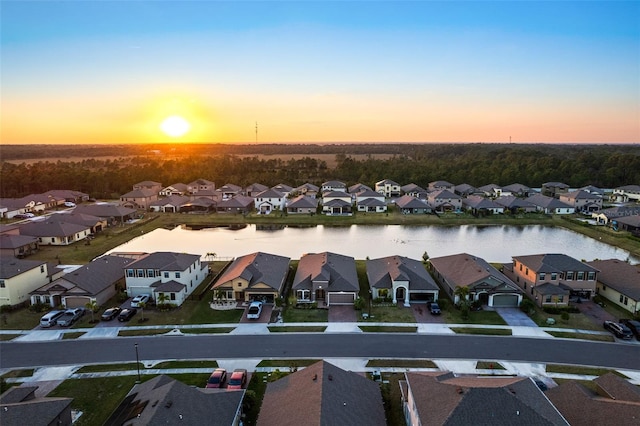 aerial view at dusk featuring a water view