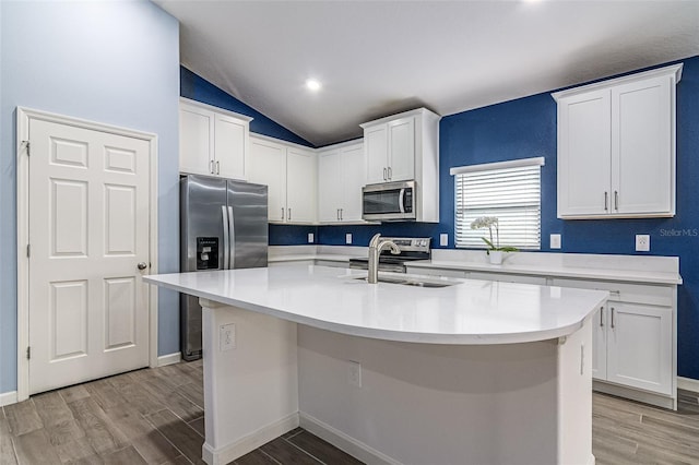 kitchen with stainless steel appliances, an island with sink, sink, and white cabinetry