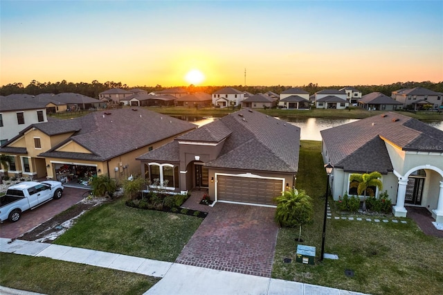 view of front of property with a garage, a lawn, and a water view