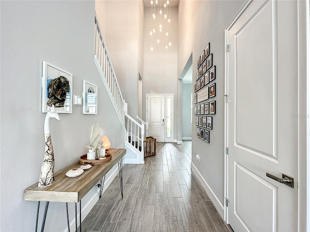 hall with hardwood / wood-style flooring and a towering ceiling