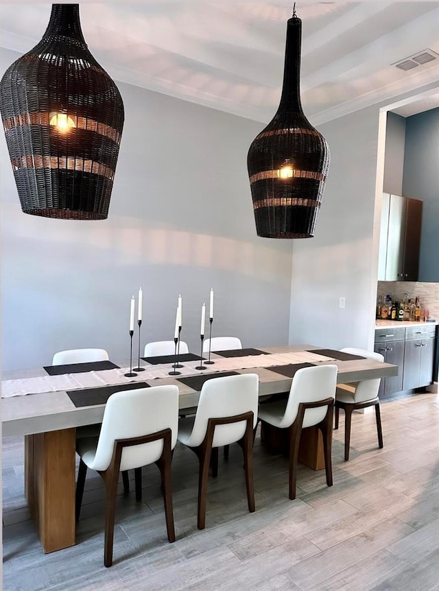 dining area with light hardwood / wood-style flooring and crown molding