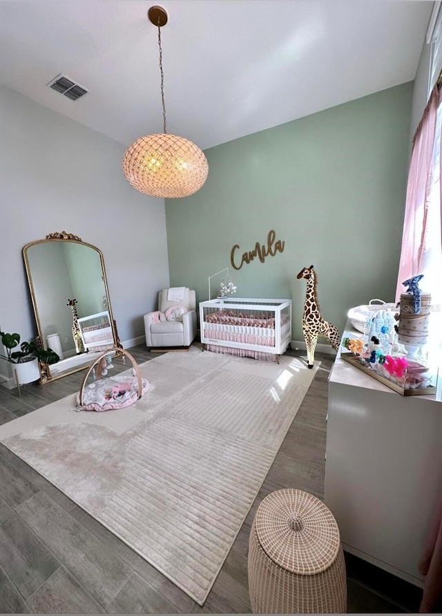 bedroom featuring dark wood-type flooring and a crib