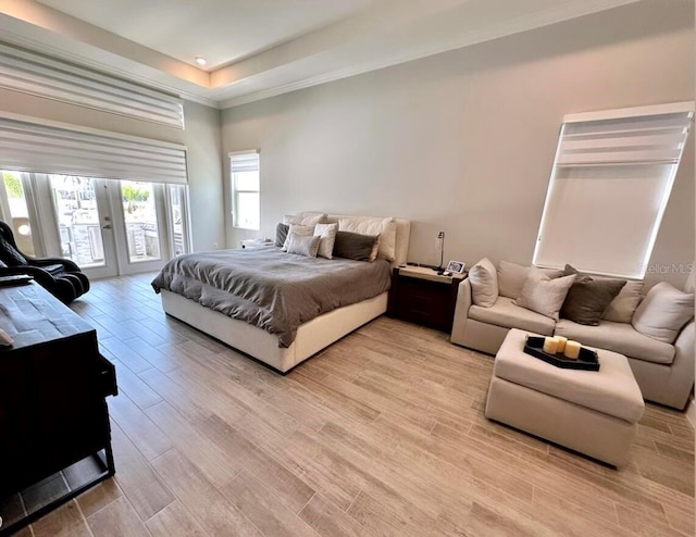 bedroom featuring access to outside, a raised ceiling, and light hardwood / wood-style flooring