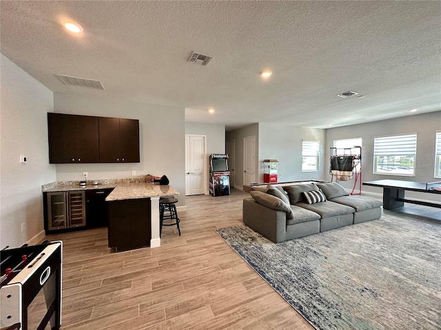 living room with a textured ceiling, light hardwood / wood-style floors, and wine cooler