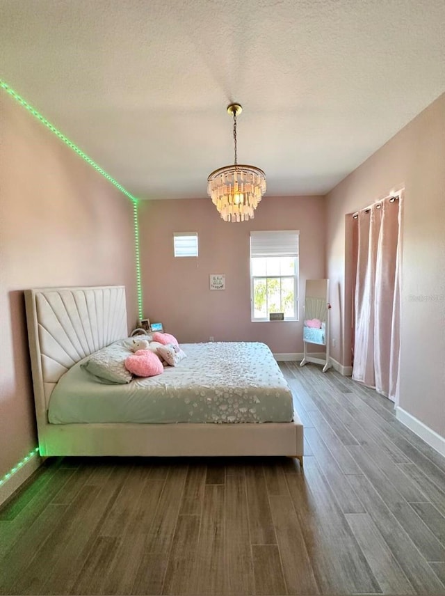 bedroom featuring hardwood / wood-style floors, a chandelier, and a textured ceiling