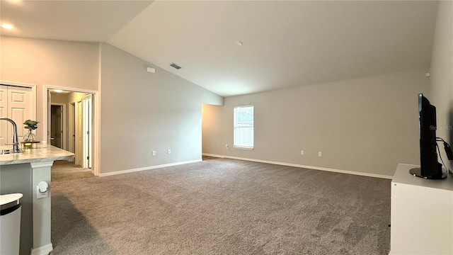 unfurnished living room with dark colored carpet, lofted ceiling, and sink