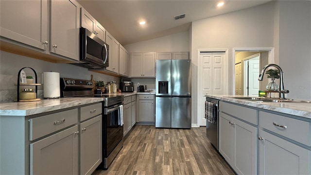 kitchen with gray cabinets, sink, stainless steel appliances, and vaulted ceiling