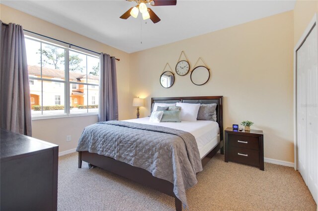 bedroom with ceiling fan, a closet, light carpet, and multiple windows