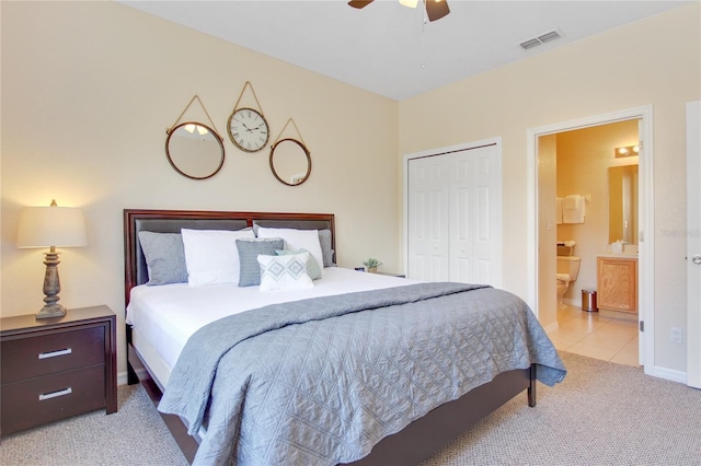 bedroom with ensuite bath, ceiling fan, a closet, and light colored carpet