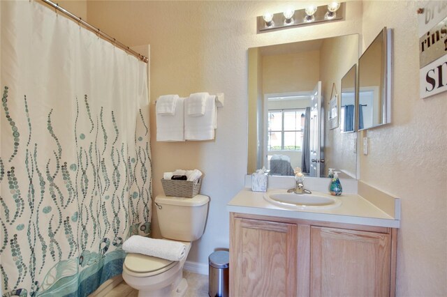 bathroom featuring vanity, curtained shower, and toilet