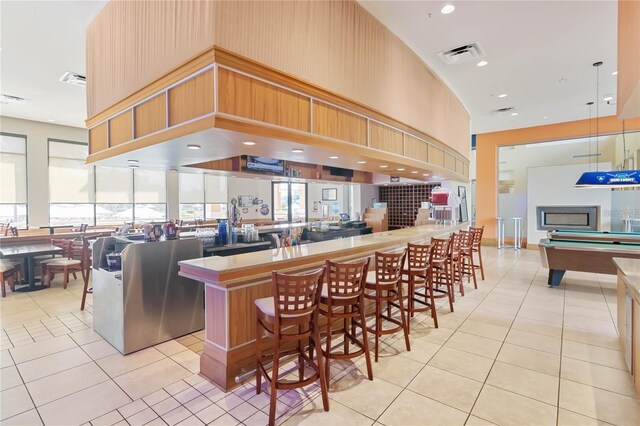 kitchen with a high ceiling, light tile patterned floors, pool table, a kitchen island, and a kitchen bar