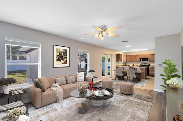 living room with ceiling fan, french doors, and light hardwood / wood-style floors