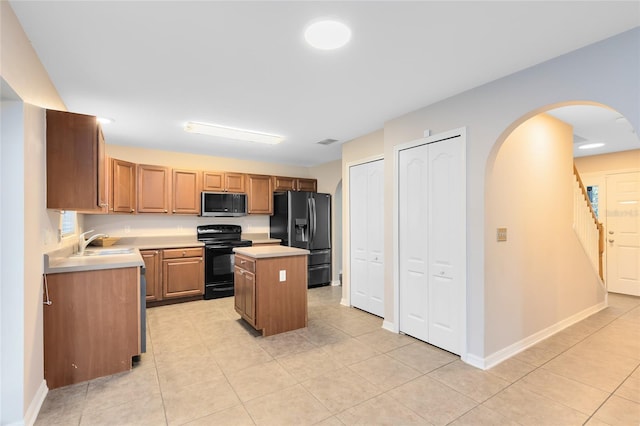 kitchen featuring a center island, light tile patterned floors, black appliances, and sink