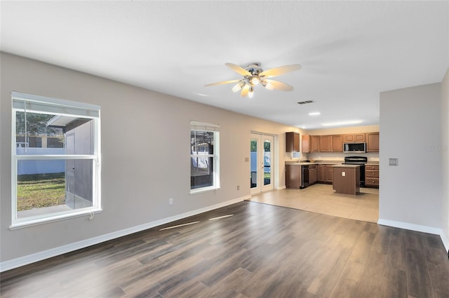 unfurnished living room with ceiling fan, sink, light hardwood / wood-style floors, and french doors