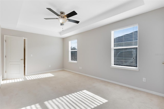 carpeted empty room featuring a tray ceiling and ceiling fan