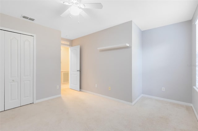 unfurnished bedroom with ceiling fan, light carpet, and a closet