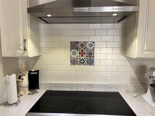 kitchen with white cabinets, wall chimney range hood, and tasteful backsplash