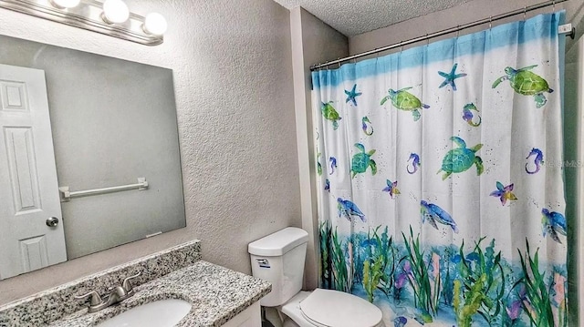 bathroom with toilet, vanity, walk in shower, and a textured ceiling