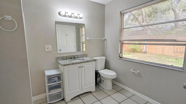 bathroom with toilet, a healthy amount of sunlight, tile patterned floors, and vanity