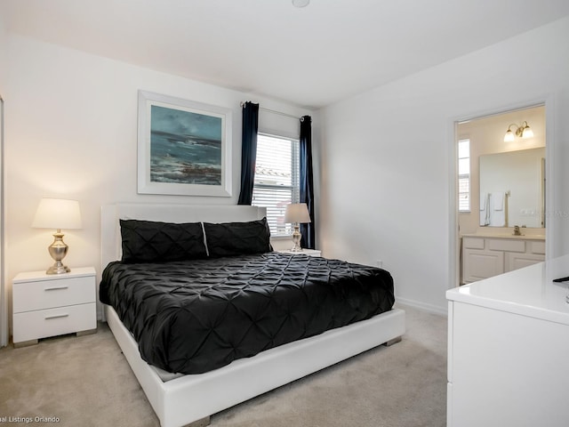 carpeted bedroom featuring connected bathroom and sink