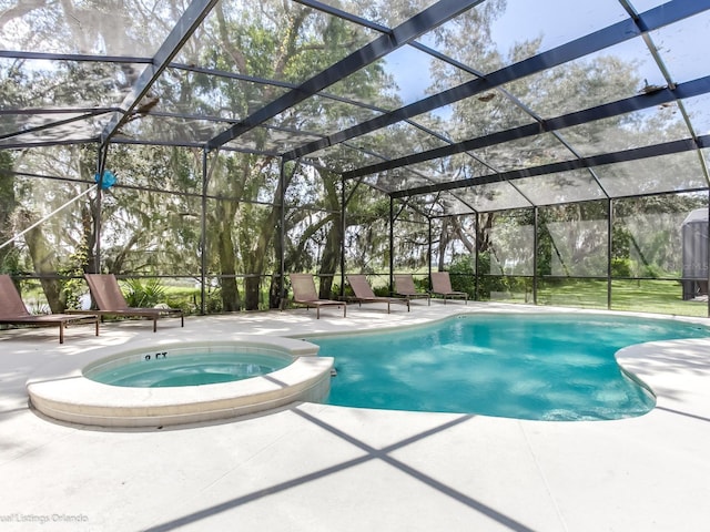 view of swimming pool featuring glass enclosure, an in ground hot tub, and a patio area