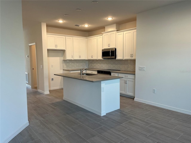 kitchen featuring white cabinets, a center island with sink, black range with electric stovetop, and sink