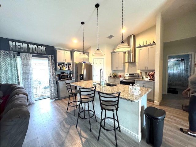 kitchen featuring appliances with stainless steel finishes, sink, gray cabinets, hanging light fixtures, and an island with sink