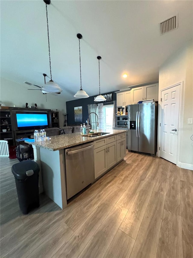 kitchen with sink, stainless steel appliances, pendant lighting, gray cabinets, and a kitchen island with sink