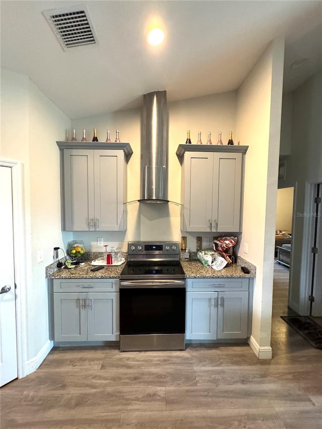 kitchen with electric range, wall chimney exhaust hood, light hardwood / wood-style floors, and stone countertops