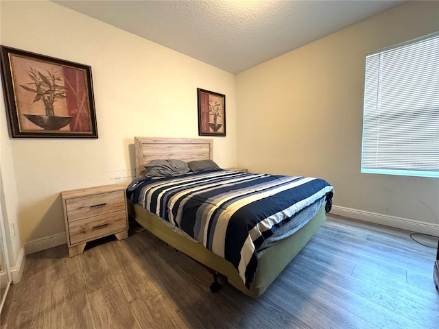 bedroom with dark hardwood / wood-style floors and a textured ceiling