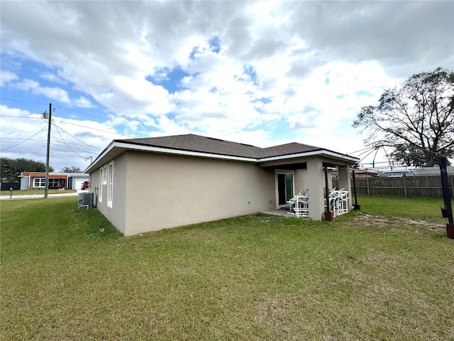 rear view of property featuring central air condition unit and a lawn