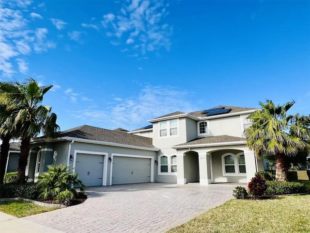 view of front of home with solar panels, a garage, and a front yard