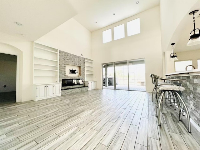 living room featuring a multi sided fireplace, built in features, and a towering ceiling