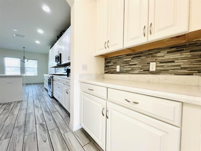 kitchen featuring white cabinets, decorative light fixtures, backsplash, and stainless steel appliances