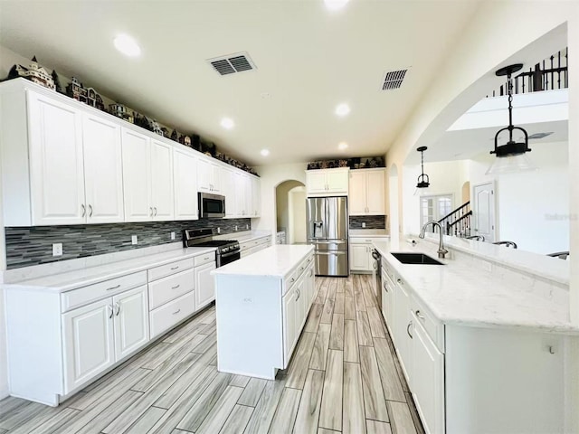 kitchen featuring pendant lighting, a spacious island, sink, white cabinetry, and stainless steel appliances