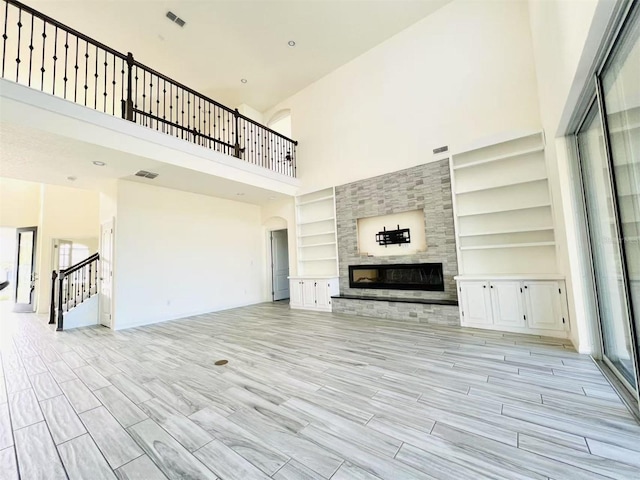 unfurnished living room with a large fireplace, built in features, and a high ceiling