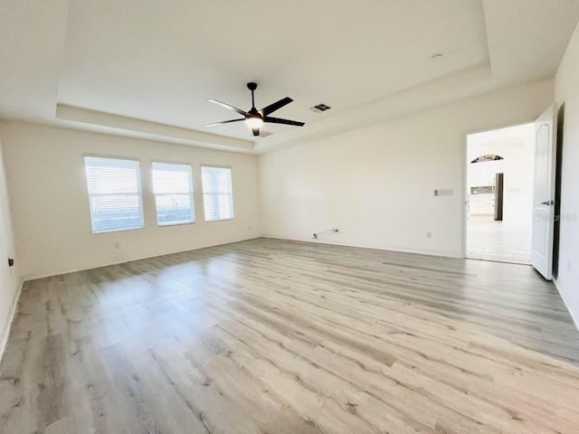 spare room featuring a raised ceiling and light hardwood / wood-style flooring