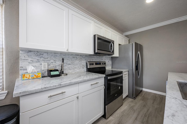 2803 E Pine St, Orlando, FL 32803 - kitchen featuring crown molding, light wood finished floors, white cabinetry, stainless steel appliances, and decorative backsplash