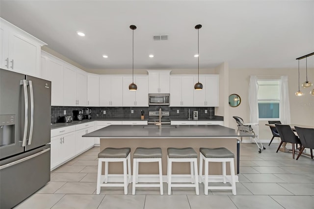 kitchen featuring stainless steel appliances, white cabinets, and decorative light fixtures