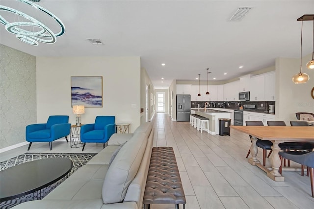 living room with sink, light tile patterned floors, and an inviting chandelier