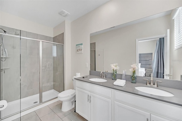 bathroom featuring toilet, tile patterned flooring, a shower with door, and vanity