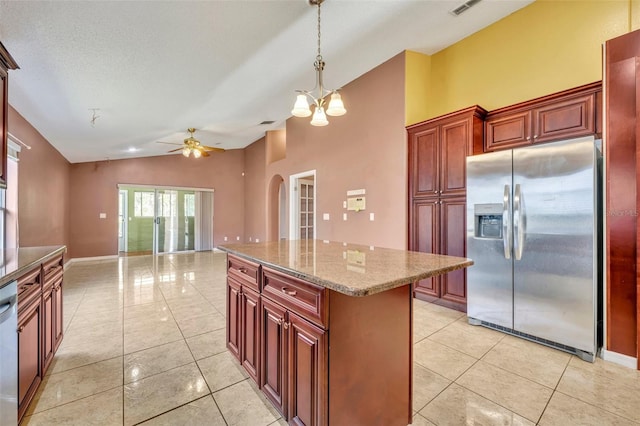 kitchen featuring stainless steel appliances, decorative light fixtures, stone counters, ceiling fan with notable chandelier, and a center island