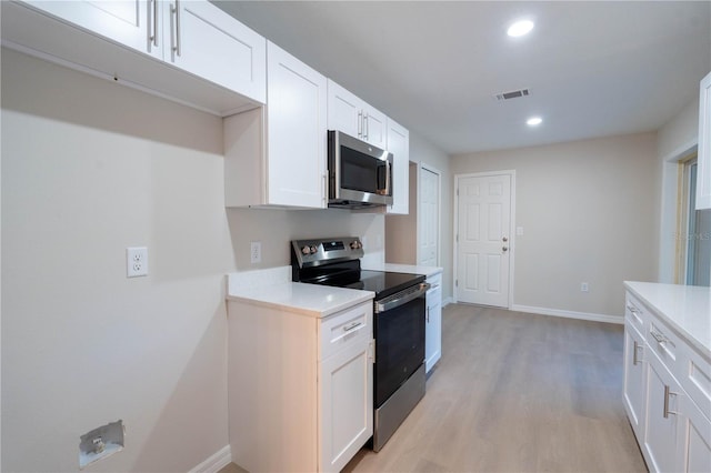 kitchen with white cabinets, appliances with stainless steel finishes, and light hardwood / wood-style floors